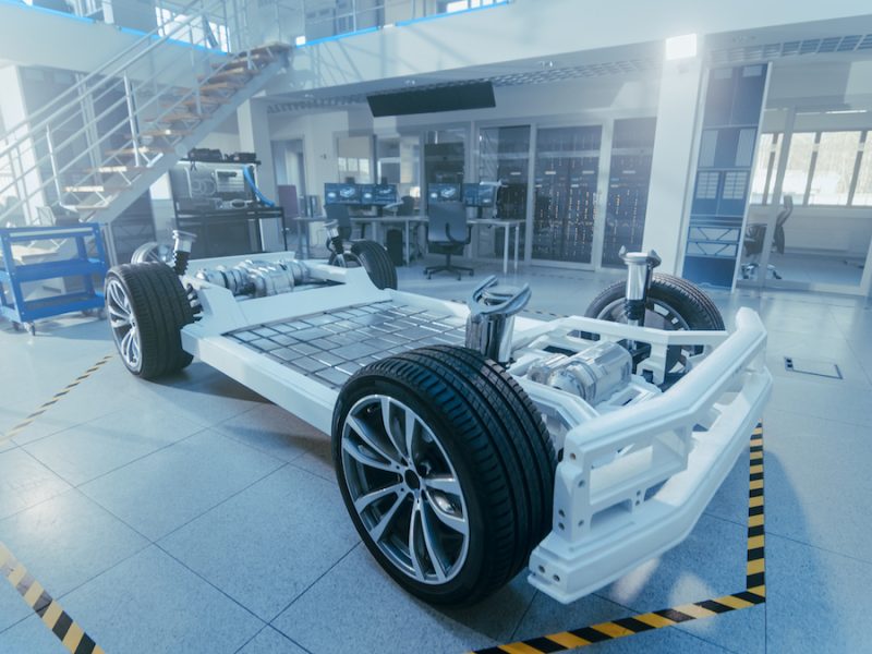Concept of Authentic Electric Car Platform Chassis Prototype Standing in High Tech Industrial Machinery Design Laboratory. Hybrid Frame include Tires, Suspension, Engine and Battery.